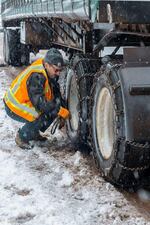 A trucker chains up on a snow-covered road on Tuesday, Nov. 26, 2019.