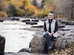 Britta Copt, a 26-year veteran of the EPA, sits on a rock at Clear Creek in Golden, Colo. She fears that former President Donald Trump will go after federal employee unions once again if he wins in November.