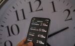 This illustration photo shows a clock in the background of a smartphone showing the time after daylight saving time was implemented in Los Angeles, Calif., on March 15, 2022.