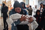 A woman mourns as she carries the shrouded body of a child killed following overnight Israeli strikes on Rafah in the southern Gaza Strip, on May 6.