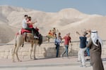 Tourists pose for photographs on camels on the road leading to the Dead Sea in the Israeli-occupied West Bank.