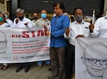 People hold posters and candles outside a Mumbai church holding a memorial mass for the Indian rights activist and Jesuit priest Father Stan Swamy on July 6, 2021. Swamy was detained for nine months without trial under Indian anti-terrorism laws, and died on July 5, 2021 ahead of a bail hearing, officials said.