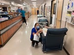 In August 2021, a nurse consults with a patient in the emergency room at Salem Hospital in Salem, Ore. Gurneys line the hallway ready to take patients if needed. Sometimes patients must stay in hallways because of a lack of available rooms.