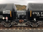 Tank cars on train tracks. A placard warns about the risks of toxic inhalation.