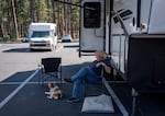 After being evacuated from their home in Whychus Canyon, Jan Saxton and his dog, Josey, relax outside their RV in the parking lot of Sisters High School. It’s Saxton’s third time being evacuated since moving to the area in 2019.