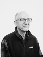 This black-and-white portrait photo shows David Fox from about the waist up. He's wearing a long-sleeved plaid shirt, a fleece vest and glasses.