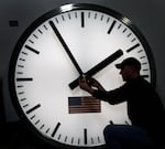 FILE: Dave LeMote uses an wrench to adjust hands on a stainless steel tower clock at Electric Time Company, Inc. in Medfield, Mass., in this March 7, 2014 photo.
