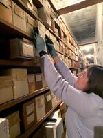 Denise Hatch retrieves a box of cremated remains from storage at Portland Memorial Funeral Home on May 17, 2024. Thousands of unclaimed remains are kept in storage.