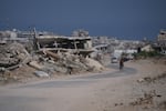 A Palestinian man rides his bicycle by the rubble of buildings that were destroyed during the Israel Hamas war, in Khan Younis, southern Gaza Strip, Friday, July 31, 2026.