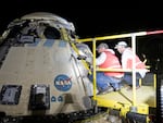This handout image supplied by NASA shows Boeing and NASA teams work around NASA's Boeing Crew Flight Test Starliner spacecraft after it landed uncrewed at White Sands Space Harbor, on Friday at White Sands, N.M.