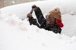 Zaria Black, 24, from Buffalo, clears off her car as snow falls Friday, Nov. 18, 2022, in Buffalo, N.Y.