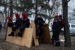 Municipal workers rest on some plywood during a break from fixing windows and clearing rubble.