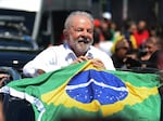 Luiz Inacio Lula da Silva holds a Brazilian flag while leaving a polling station in Sao Paolo during Sunday's presidential runoff election.