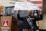 Cheng "Charlie" Saephan holds display check above his head after speaking during a news conference where it was revealed that he was one of the winners of the $1.3 billion Powerball jackpot at the Oregon Lottery headquarters on Monday, April 29, 2024, in Salem, Ore.