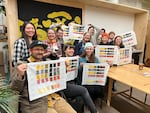 Students at the WildCraft Studio School in Portland hold up their mushroom color charts with instructor Julie Beeler (center, in denim apron) on Dec. 8, 2022.