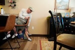 Neil Petersen sits in a chair as Jack, 4, plays underneath him.