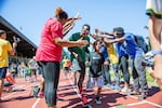 Throwers make a tunnel for kids and pros running in the Community Half-Lap at the end of the meet.