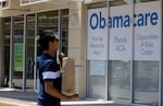 FILE -  A man walks by an healthcare insurance office in Hialeah, Fla., July 27, 2017.