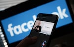 In this illustration photo taken in Los Angeles on October 28, 2021, a person watches on a smartphone as Facebook CEO Mark Zuckerberg unveils the Meta logo.
