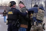 FILE - Law enforcement detain a man outside the Bishop Henry Whipple Federal Building during a protest, Jan. 17, 2026, in Minneapolis.