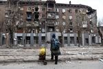 A local resident looks at a damaged apartment building during heavy fighting near the Illich Iron & Steel Works Metallurgical Plant, the second largest metallurgical enterprise in Ukraine, in an area controlled by Russian-backed separatist forces in Mariupol, Ukraine, Saturday, April 16, 2022. Mariupol, a strategic port on the Sea of Azov, has been besieged by Russian troops and forces from self-proclaimed separatist areas in eastern Ukraine for more than six weeks.