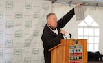 Person standing at lectern holds up a piece of paper to an unseen crowd