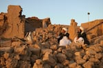 Afghan residents sit at a damaged house after an earthquake in a village in Herat province on Saturday.