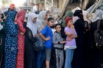 Palestinian women line up to buy fresh bread next to destroyed buildings at the Nuseirat refugee camp in the central Gaza Strip on Nov. 4, 2023.