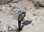 A porter carries a barrel of human waste from Mount Everest base camp to the small village of Gorak Shep.