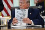 President Donald Trump holds papers in the Oval Office of the White House before signing an executive order Tuesday, March 31, 2026, in Washington.