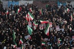 Veiled Iranian women hold Iran flags and placards while attending a pro-government rally in Tehran, in December 2022. The rally was held in opposition to unrest following the death of 22-year-old Mahsa Amini in police custody in September 2022.