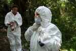 Yoltzi Martinez, 38, (right), from Guerrero, Mexico, dons a protective uniform to enter the area where a group of family members and forensic experts are searching for human remains.
