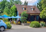 A house converted into a tap house in Ashland, Oregon. Tables with blue umbrellas are set up outside.