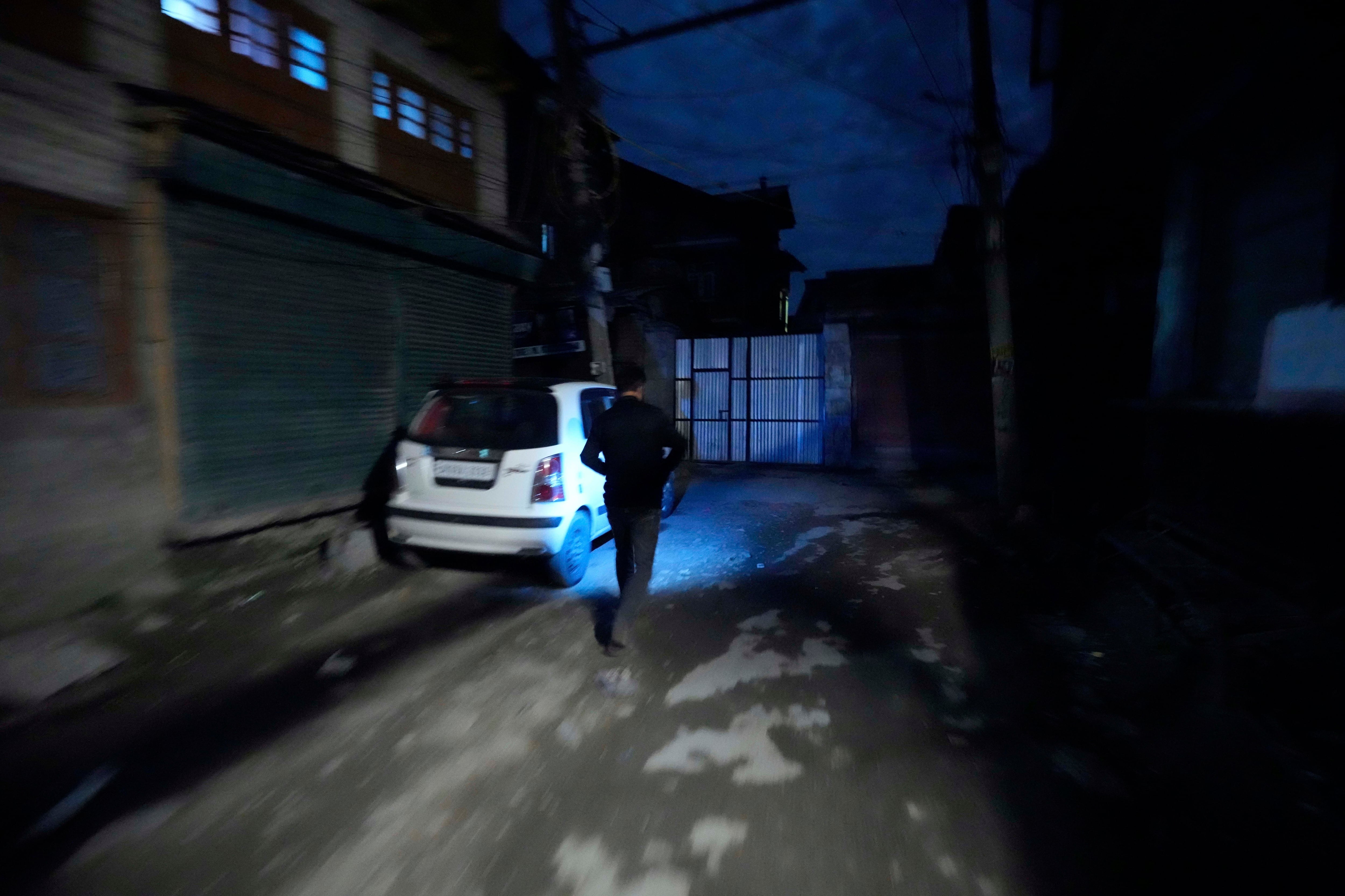 A Kashmiri man using a cellphone light during a blackout is seen after residents of the city of Jammu reported hearing explosions and sirens in Srinagar, Indian-controlled Kashmir, Thursday.