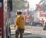 A firefighter walks between multiple fire engines as multiple fire crews and other emergency personnel monitor and battle a fire in downtown Portland, Ore., on Aug. 2, 2026. The fire was at an abandoned building on northwest Naito Parkway.