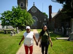 Karen Williams (left) holds hands with her daughter, Lena Powell, while walking through St. Michael's Lutheran Churchyard in Philadelphia. Williams, who is disabled, bought a life insurance policy to pay for her funeral, but it caused her to lose access to Supplemental Security Income (SSI) benefit checks that she relies on to pay bills.
