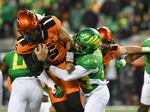 Oregon State quarterback DJ Uiagalelei (5) is tackled by Oregon defensive back Evan Williams, front right, during the first half of an NCAA college football game Friday, Nov. 24, 2023, in Eugene, Ore.