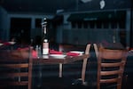 A with dishes, napkins  and a bottle of wine on top, in an empty restaurant dining room.