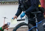 FILE - Portland police central bike squad officer Joey Yoo issues a citation for drug possession in the city’s Old Town neighborhood in downtown Portland, Ore., Nov. 15, 2023, along with a card with the phone number for treatment information.