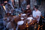 Server Luis Velez opens a bottle of wine for customers Mary Graf, left, Sophie Mandel and Andy Peraza, right, shown through a sheet of plastic surrounding the table, on Wednesday, October 21 , 2020, at Spinasse on Capitol Hill in Seattle.