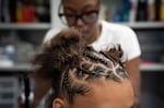 Jayda, 16, gets her hair braided by Chrystal Thompson. Thompson visits the facility every two weeks to work on the student's hair and helps mentor trainees.