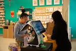 Jennee Edwards, left, pays for her groceries at Tomi Mart. Edwards, 42, says she used to shop at places like H Mart and Uwajimaya in Portland before moving to Central Oregon. Now she find most of the Asian cuisine ingredients she needs at Tomi Mart.