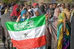 A woman displays the Somaliland flag as people queue to cast their votes during the 2024 Somaliland presidential election at a polling station in Hargeisa, Somaliland, Wednesday, Nov. 13,2024.