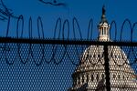 The Dome of the Capitol Building is visible through razor wire installed on top of fencing on Capitol Hill in Washington, Thursday, Jan. 14, 2021.