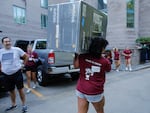 A student carries a refrigerator as new students arrive during move in day at the Fordham University Bronx campus, Aug. 25, 2024, in New York. 