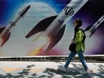 A woman walks past a banner showing missiles being launched, in northern Tehran, Iran, on Friday.