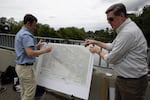 Josh Elliott, left, a bio-remediation engineer with Maul Foster Alongi, sets up a map of the cleanup plan along the Columbia Slough on July 10, 2023.