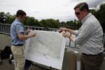 Josh Elliott, left, a bio-remediation engineer with Maul Foster Alongi, sets up a map of the cleanup plan along the Columbia Slough on July 10, 2023.