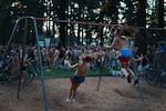 A couple of friends swing among thousands of fellow nude participants. Mount Scott Park provides 11 acres recreational facilities among numerous trees.
