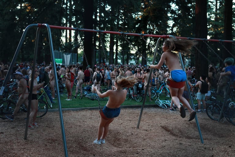 A couple of friends swing among thousands of fellow nude participants. Mount Scott Park provides 11 acres recreational facilities among numerous trees.